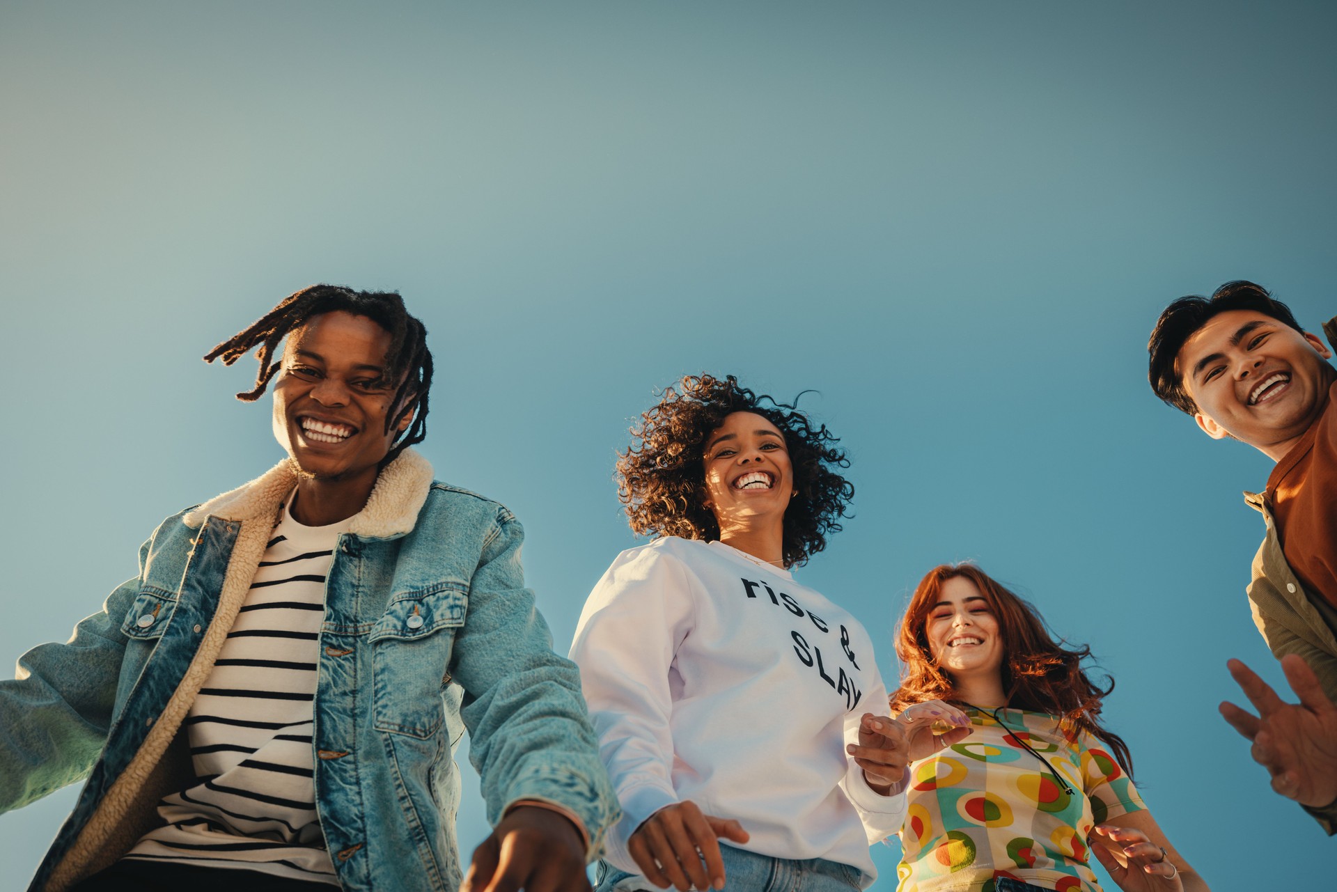 De jeunes amis heureux profitent du temps passé ensemble en plein air sous le ciel bleu