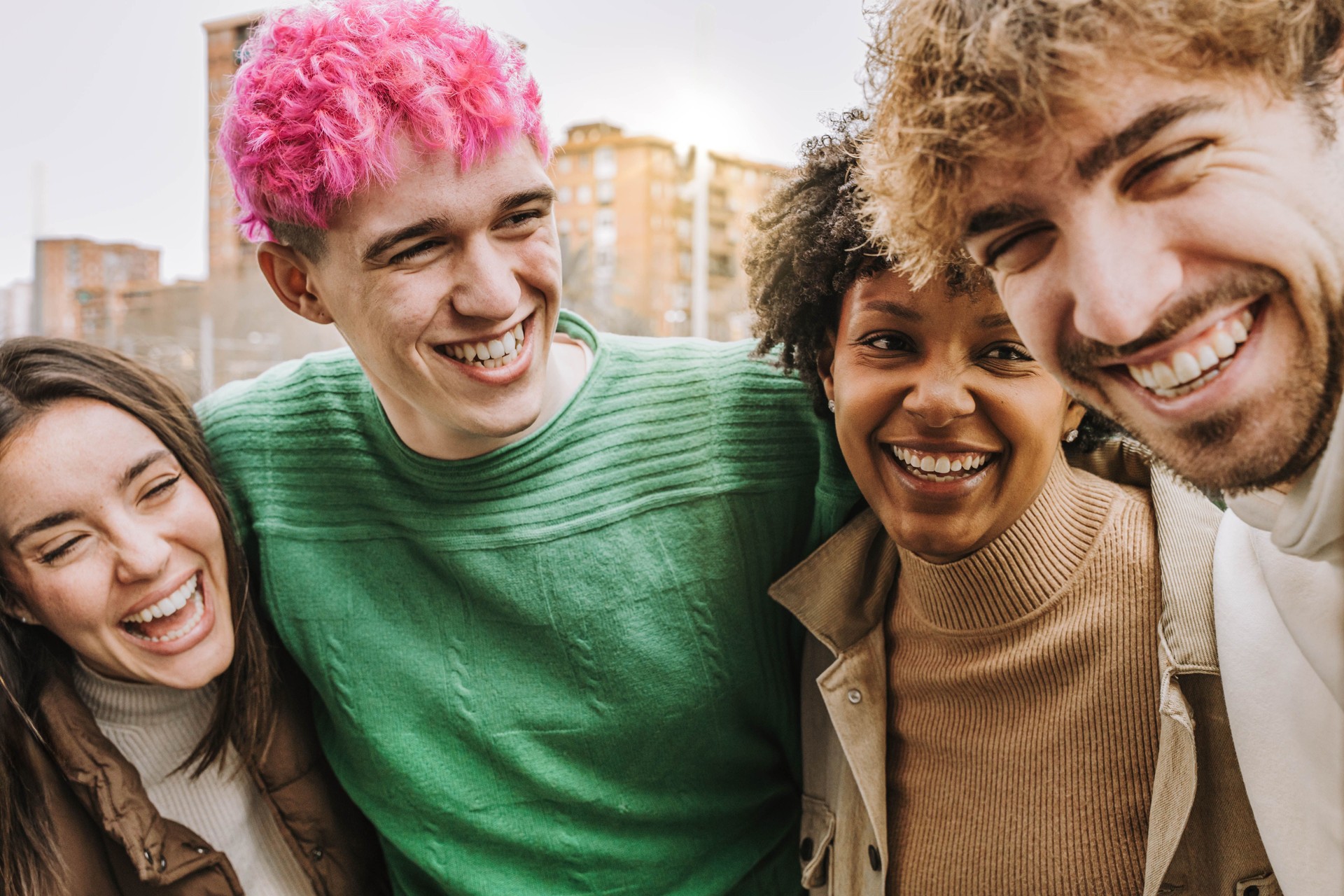 Amis heureux qui s’amusent à rire ensemble - Groupe de personnes multiraciales s’embrassant et souriant à l’extérieur - Concept de personnes et d’amitié