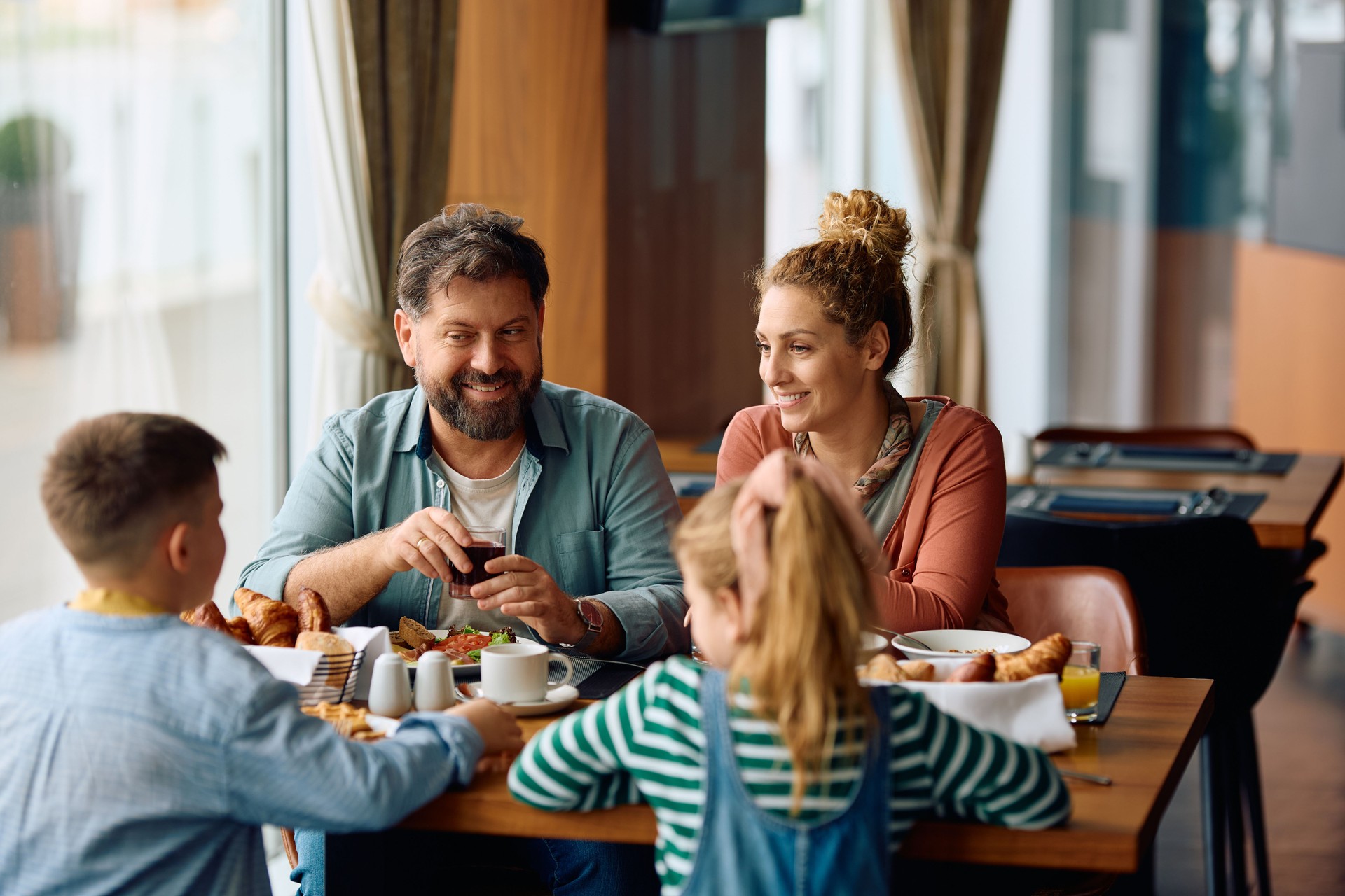 Joyeuse famille discutant tout en prenant le petit-déjeuner dans un restaurant de l’hôtel.
